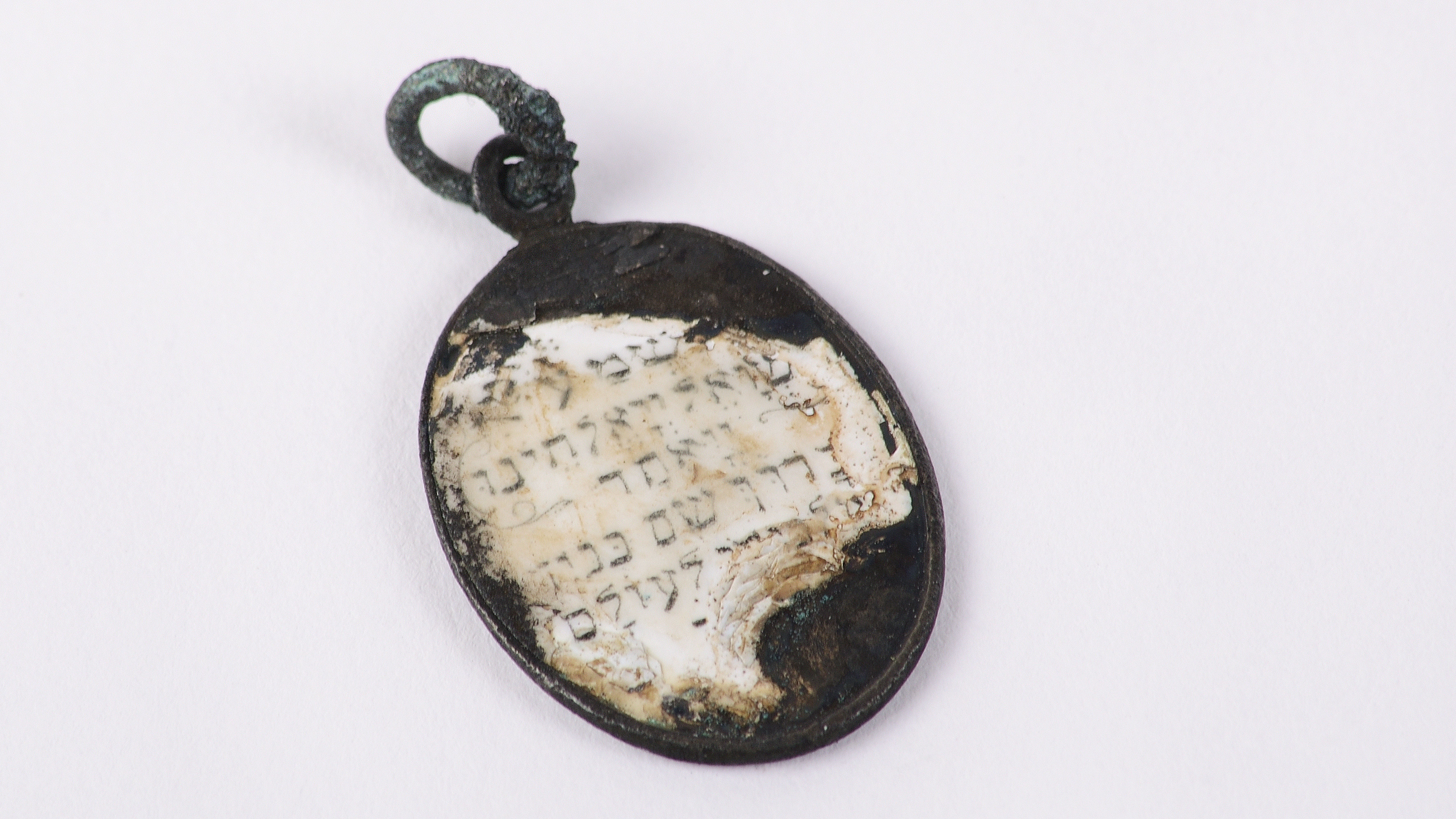 Das Bild zeigt ein Medaillon eines jüdischen Häftlings, welches als Aufschrift das Stoßgebet ,,Schima Israel”, das von Juden in großer Not gesprochen wird, gedruckt hat.