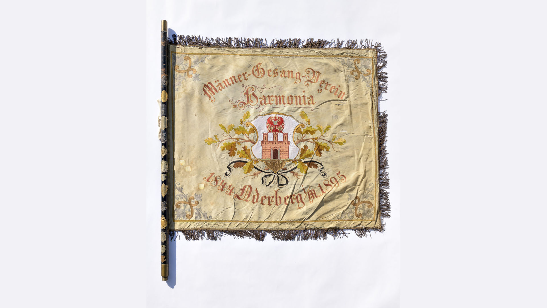 Foto: Fahne eines Männergesangsvereins in der Mitte mit Wappen und Eichelblättern verziert